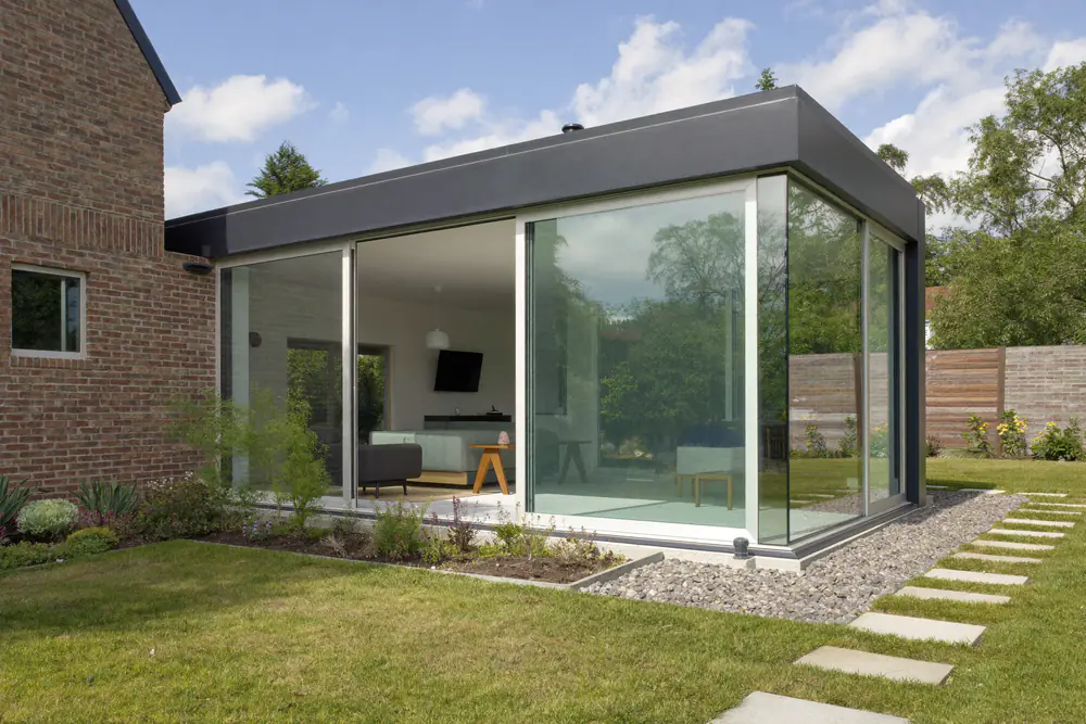Uitbouw aan een woning met net geplaatste grote glazen schuifdeuren