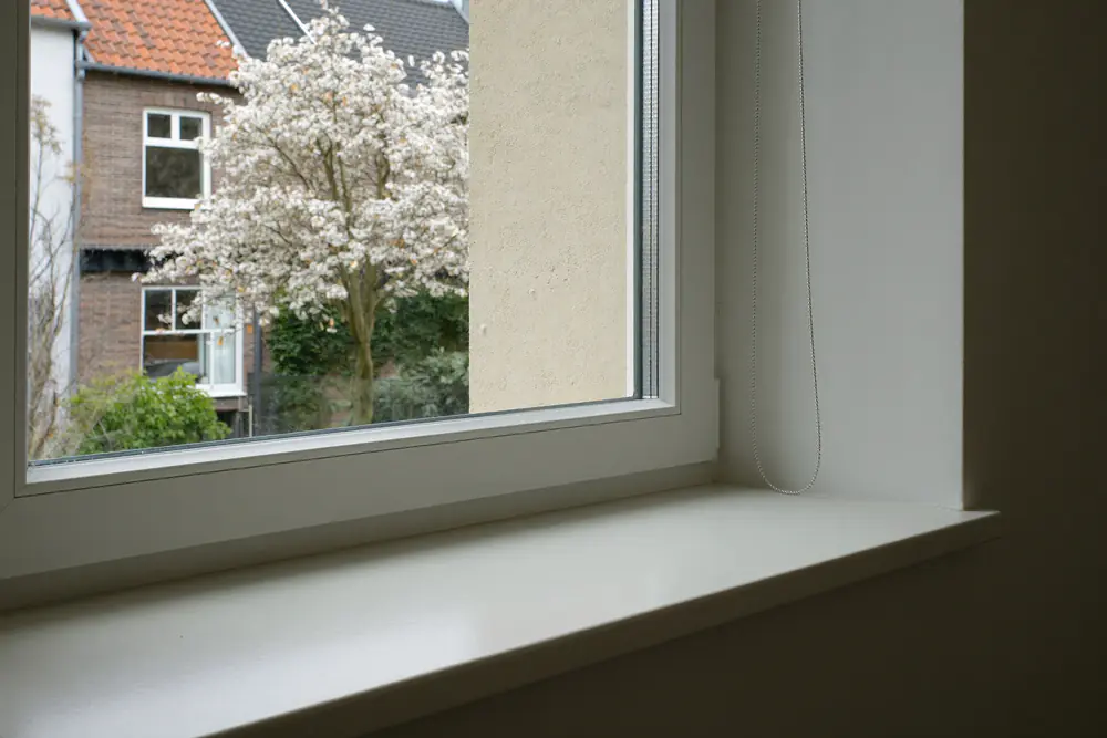 Netjes afgewerkte binnenzijde van een nieuw raam met een witte vensterbank
