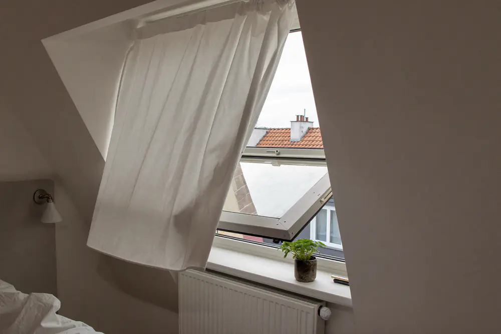 Raam in kiepstand in een slaapkamer met een plantje op de vensterbank