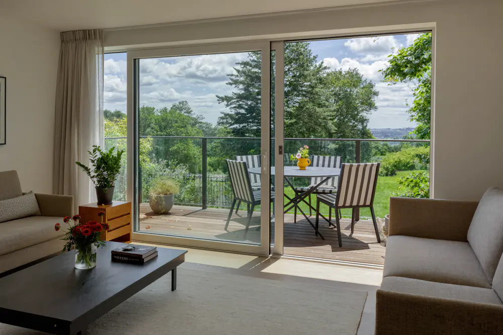 Woonkamer met een grote open schuifpui naar een terras in de zon