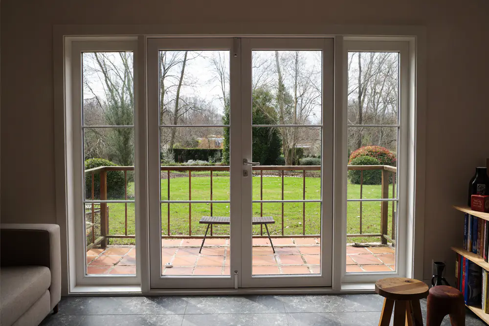 Openslaande tuindeuren met witte kozijnen die uitkomen op een terras en gazon
